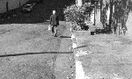 Fotografia em preto e branco uma pessoa idosa descendo uma rua