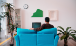 Fotografia de homem de costas sentado em sofá assistindo TV