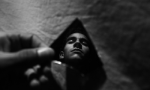 Homem segurando o pedaço de um espelho no qual seu rosto está refletido