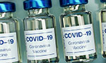Foto: fracos de vacina dispostos em série. Os recipientes parecem ser de vidro e apresentam o texto “COVID-19 Coronavirus Vaccine”.