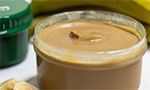 Imagem produzida com inteligência artificial: um pote de plástico sem tampa e com um creme marrom, ao lado pedaços de banana. Na parte de trás, um pote fechado e duas bananas.