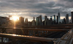 Imagem de uma ponte sendo iluminada pelo sol e, ao fundo, uma cidade com vários prédios.