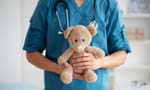 Profissional da saúde, com um estetoscópio pendurado no pescoço, segurando um urso de pelúcia.
