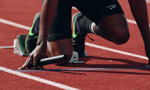 Pessoa negra em posição de largada para corrida.