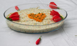 Travessa de vidro com arroz temperado. Em cima do arroz há um coração desenhado com cenoura ralada e algumas flores. O prato foi feito no “Projeto Terrapia: alimentação viva e agroecologia na promoção da saúde”.