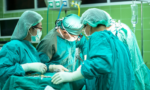 Fotografia com médicos em uma sala realizando uma cirurgia