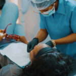 Fotografia de uma jovem sendo atendida por uma dentista.
